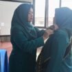 Ketua TP PKK Kecamatan Bojongsari, Cing Ovi saat menyematkan pin PKK kepada Ketua TP PKK Kelurahan Pondok Petir, Indri Lestari saat pelantikan pengurus PKK Kelurahan Pondok Petir di kelurahan setempat. (Rahcmat CH)